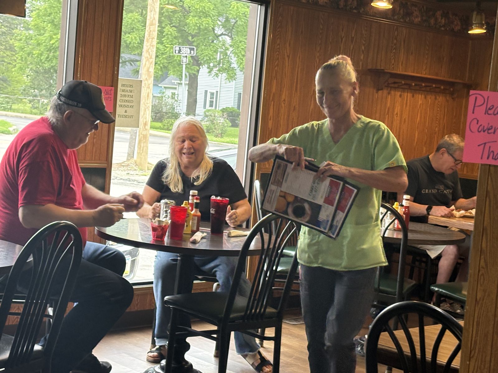 A server bringing menus to guests at a window table