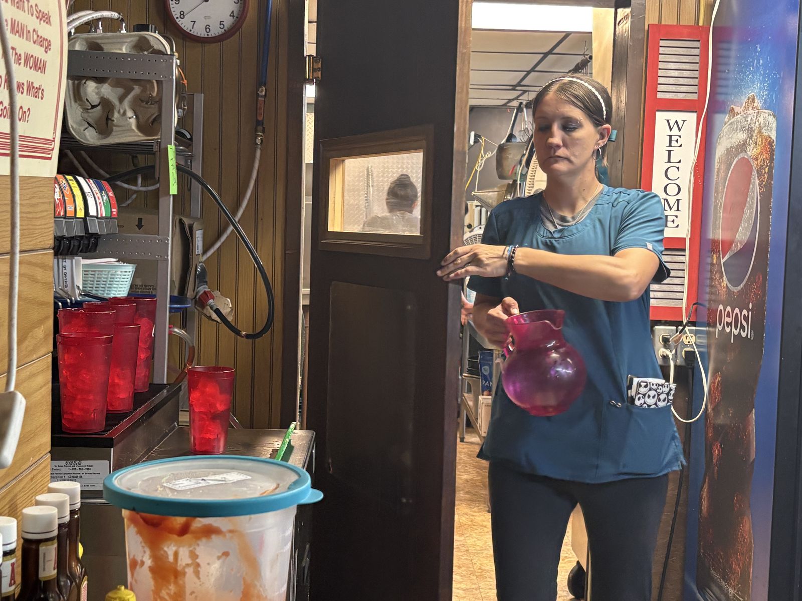 A server carrying a pitcher past the kitchen door