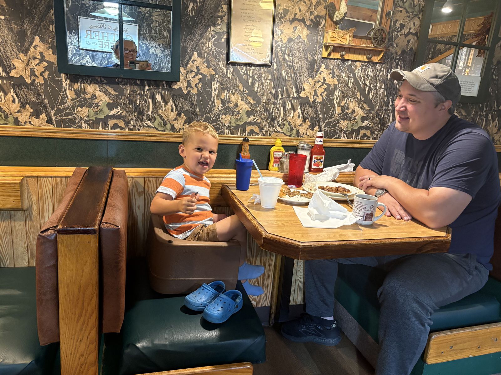 A father and his laughing son at a booth over breakfast