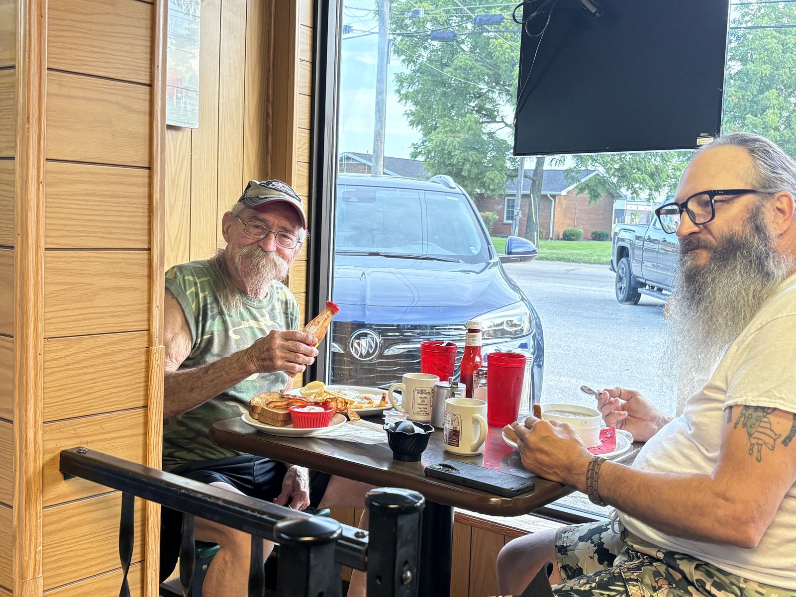 Two friends sharing breakfast at a table by the front window