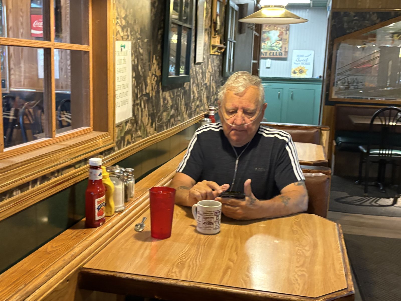 A gentleman reading his phone over morning coffee in a booth