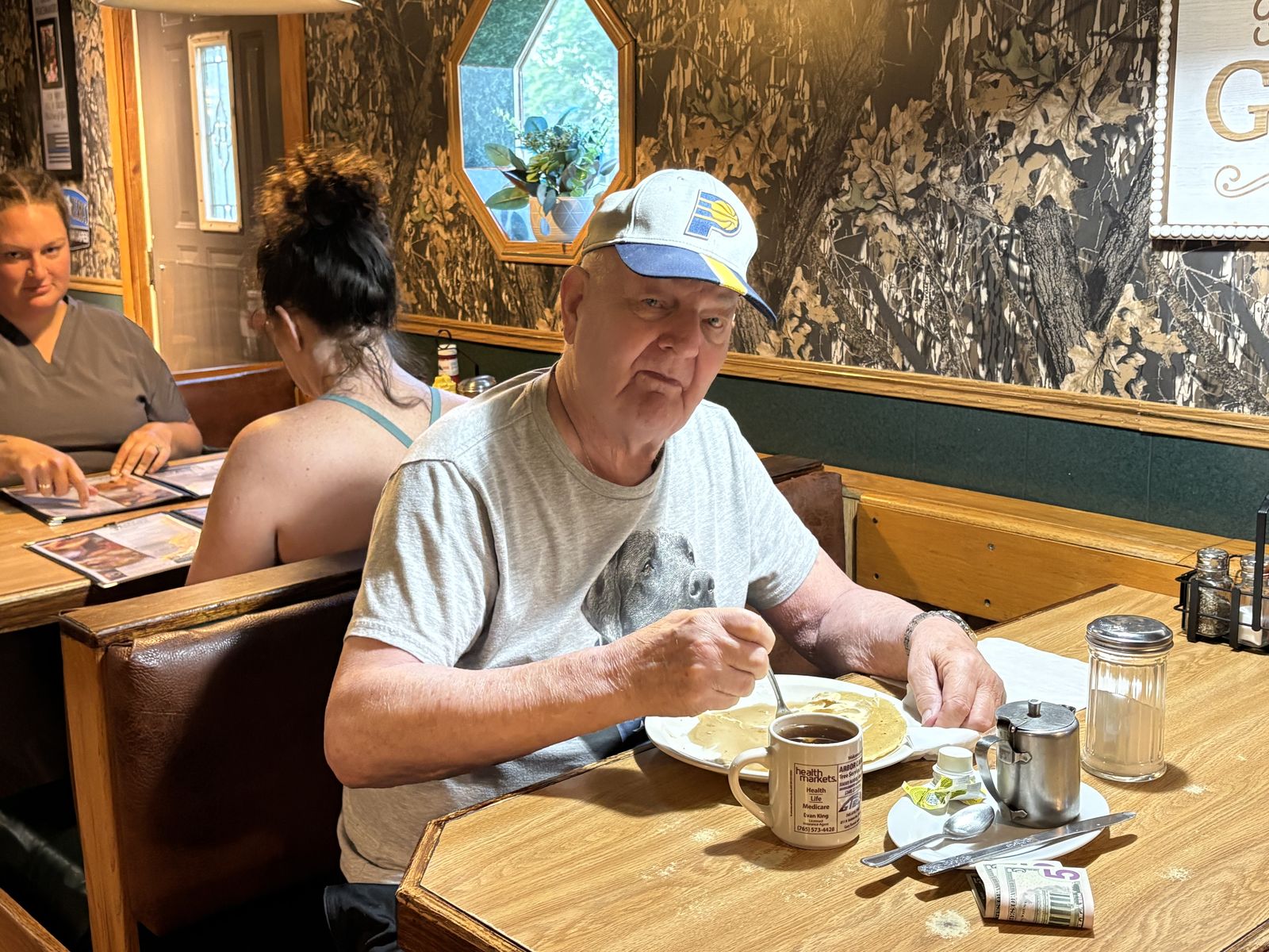 A regular in a ball cap buttering a stack of hot cakes